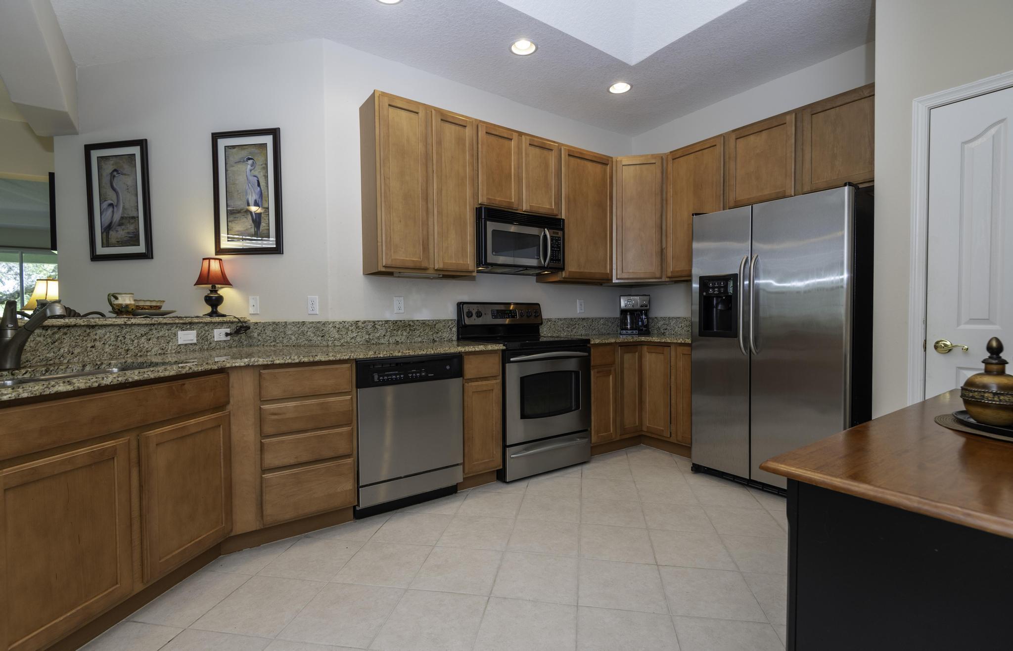 511 Northwest Red Pine Way Jensen Beach, FL 34957 - Photo 21 of 60 a kitchen with granite countertop stainless steel appliances a refrigerator a stove a sink a counter space and cabinets