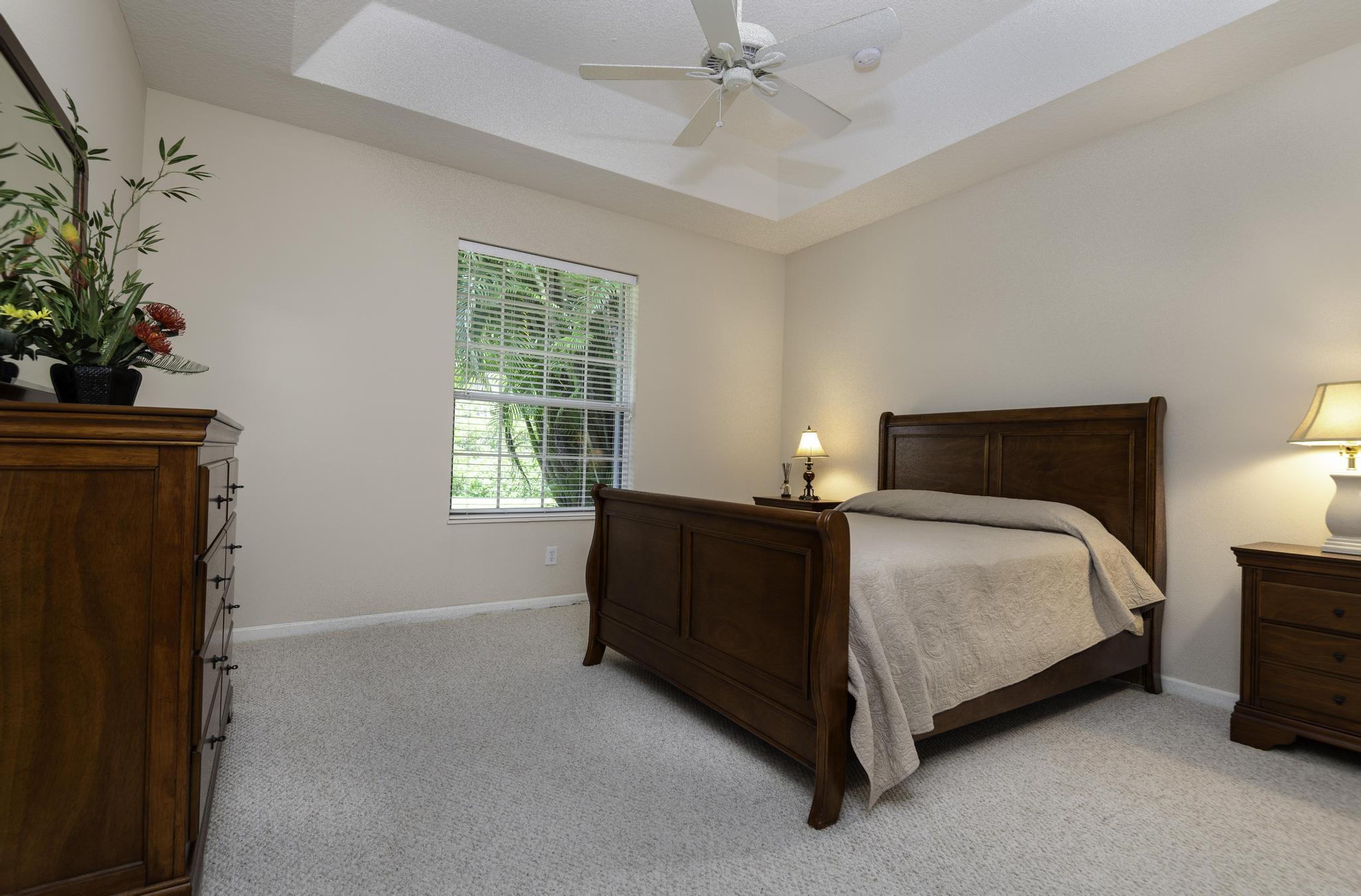 511 Northwest Red Pine Way Jensen Beach, FL 34957 - Photo 27 of 60 a bedroom with a bed lamp and a potted plant