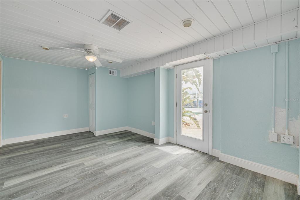 8100 Brighton Drive Port Richey, FL 34668 - Photo 13 of 68 an empty room with wooden floor chandelier fan and windows