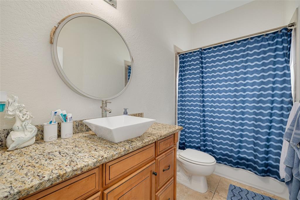 8100 Brighton Drive Port Richey, FL 34668 - Photo 26 of 68 a bathroom with a granite countertop toilet a sink and a mirror