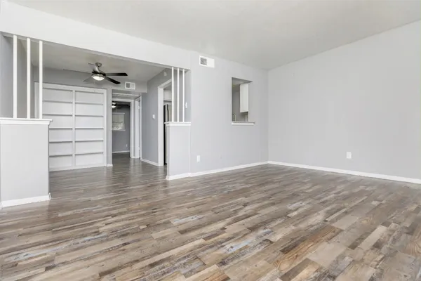 a view of an empty room with wooden floor and a window