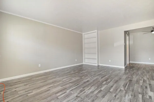 an empty room with a ceiling fan and wooden floor