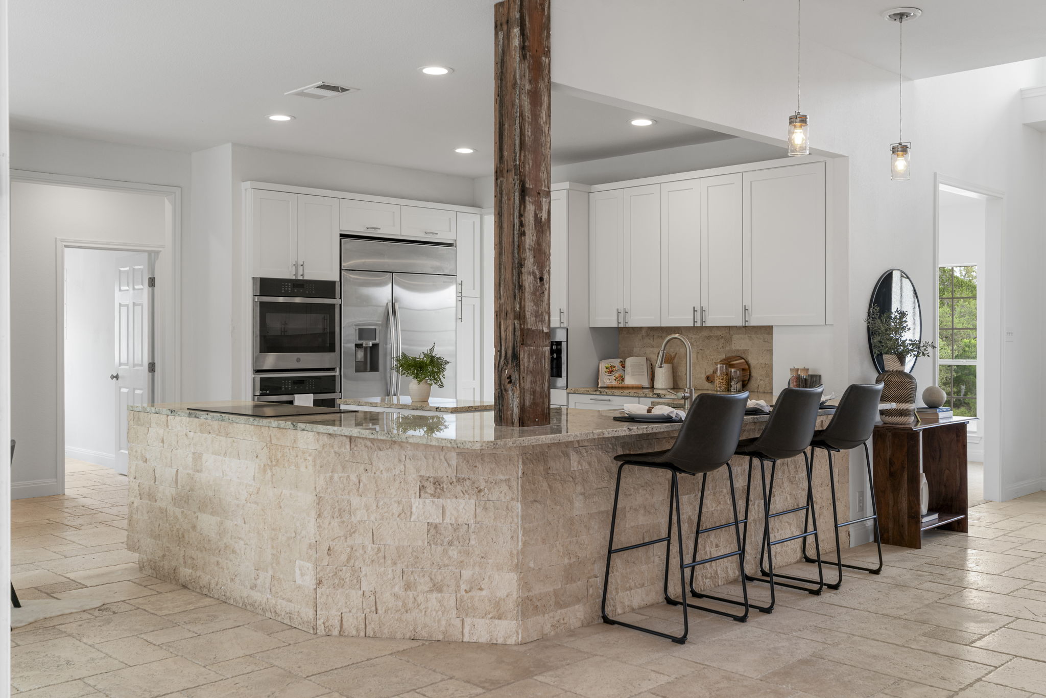 1129 Cedar Pass Road Driftwood, TX 78619 - Photo 7 of 40 This island is a total showstopper. It’s wrapped in the same stone as the exterior, topped with gorgeous granite, and anchored by a reclaimed wood support beam that adds so much character.