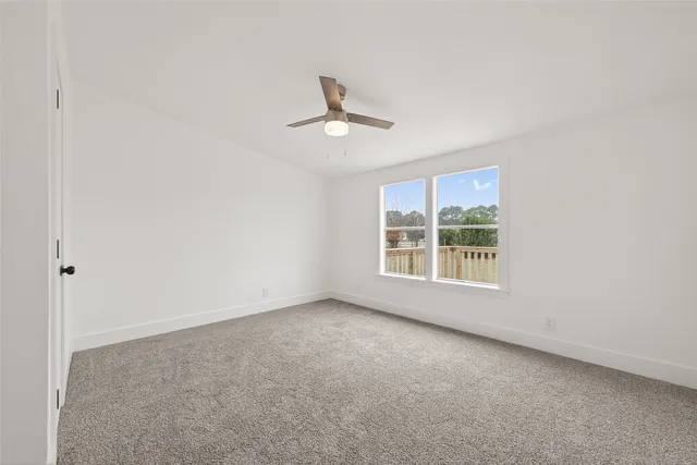 an empty room with a window and a ceiling fan