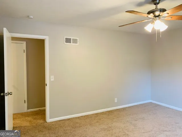 an empty room with a window and chandelier fan