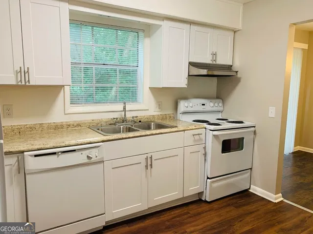a kitchen with granite countertop white cabinets and white appliances
