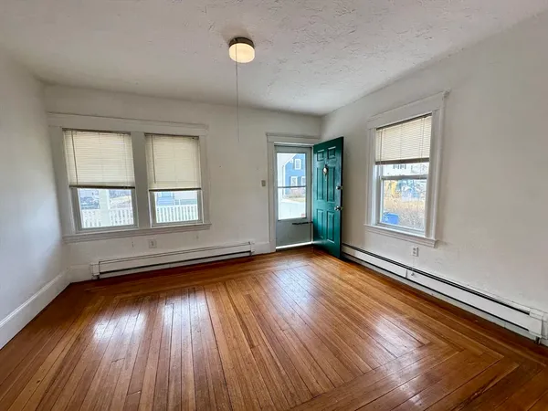 an empty room with wooden floor and windows