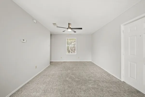 an empty room with a ceiling fan and window