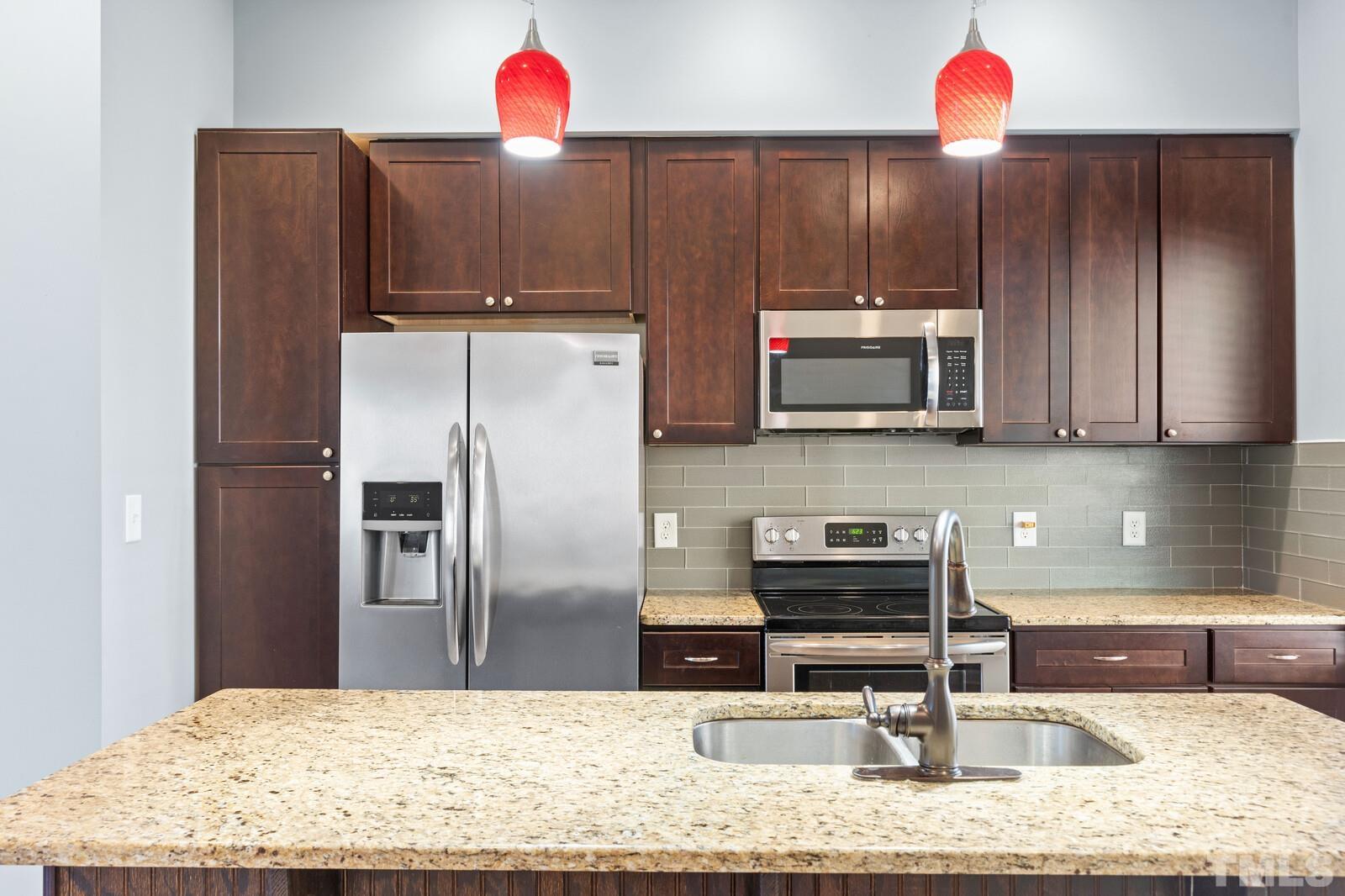 129 Pineland Circle, Unit 100 Raleigh, NC 27606 - Photo 22 of 29 a kitchen with stainless steel appliances kitchen island granite countertop a refrigerator and a stove top oven