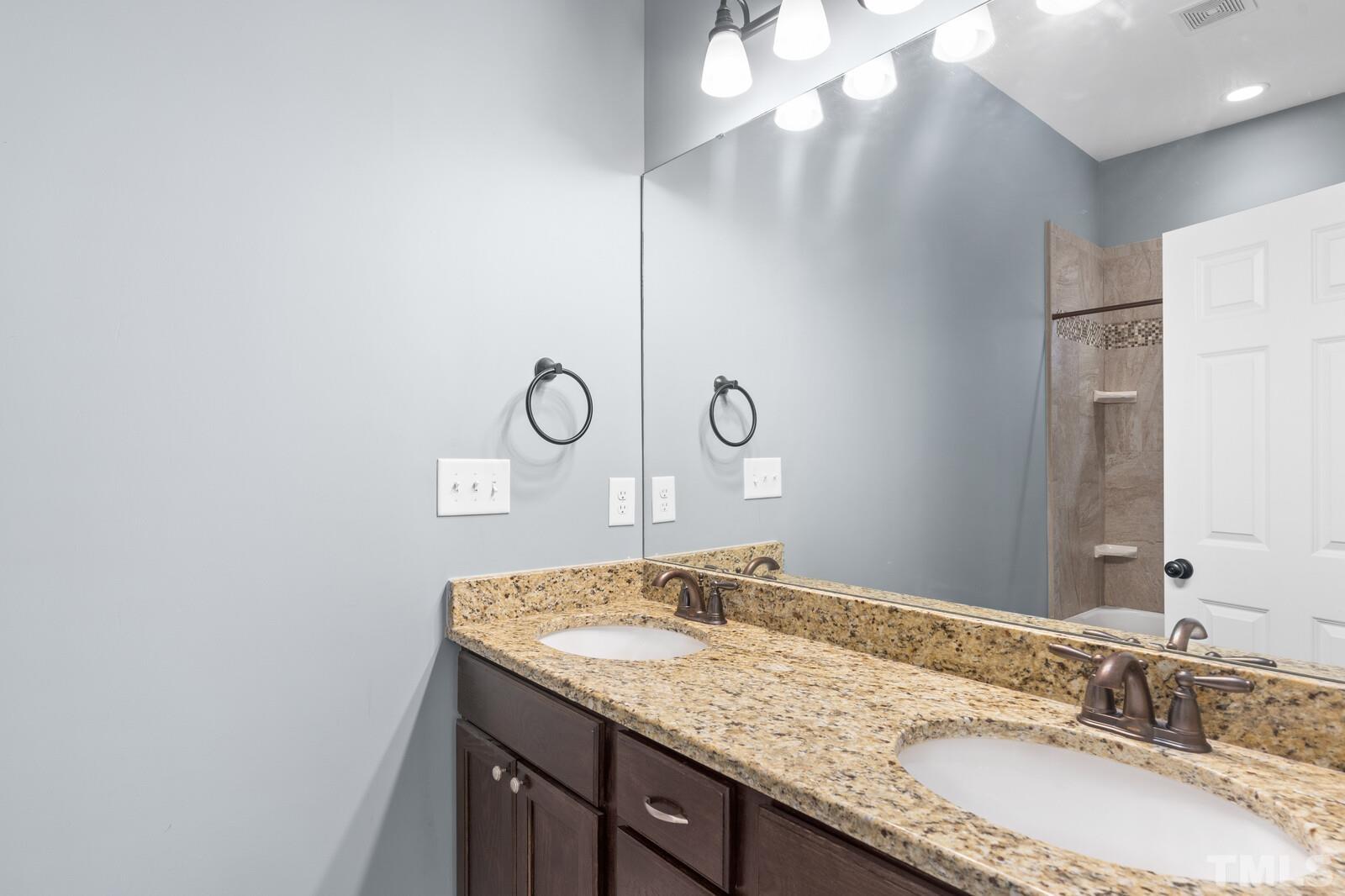 129 Pineland Circle, Unit 100 Raleigh, NC 27606 - Photo 23 of 29 a bathroom with a granite countertop sink and a mirror