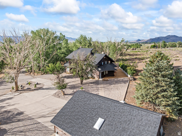 460 Omni Point Road Central Valley, UT 84754 - Photo 100 of 101 Expansive property with a dark-sided main residence, a concrete driveway, a gravel parking area, mature trees, and a mountain backdrop