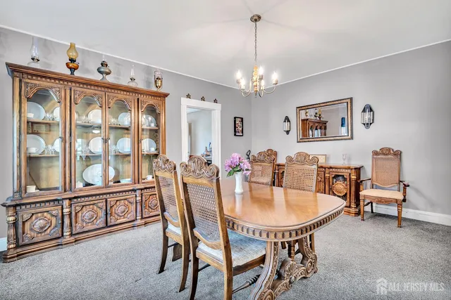 a view of a dining room with furniture a chandelier and a window