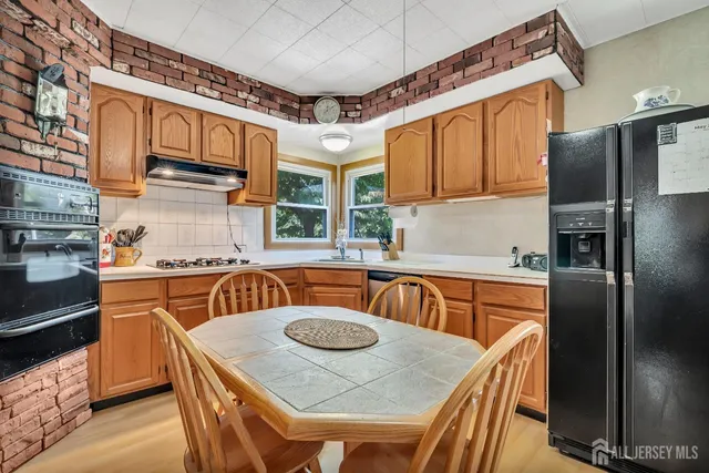 a kitchen with stainless steel appliances granite countertop a sink a stove a refrigerator with a dining table and chairs