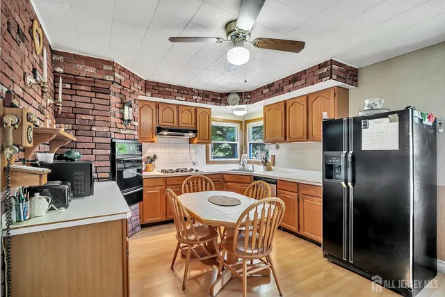 a kitchen with stainless steel appliances granite countertop a sink a stove a refrigerator cabinets and chairs