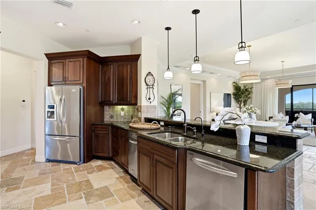 a kitchen with stainless steel appliances granite countertop a sink a stove a refrigerator and island