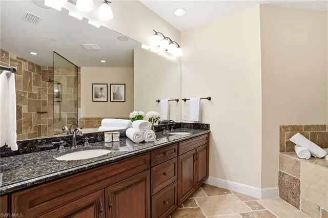 a spacious bathroom with a granite countertop double vanity sink and a mirror