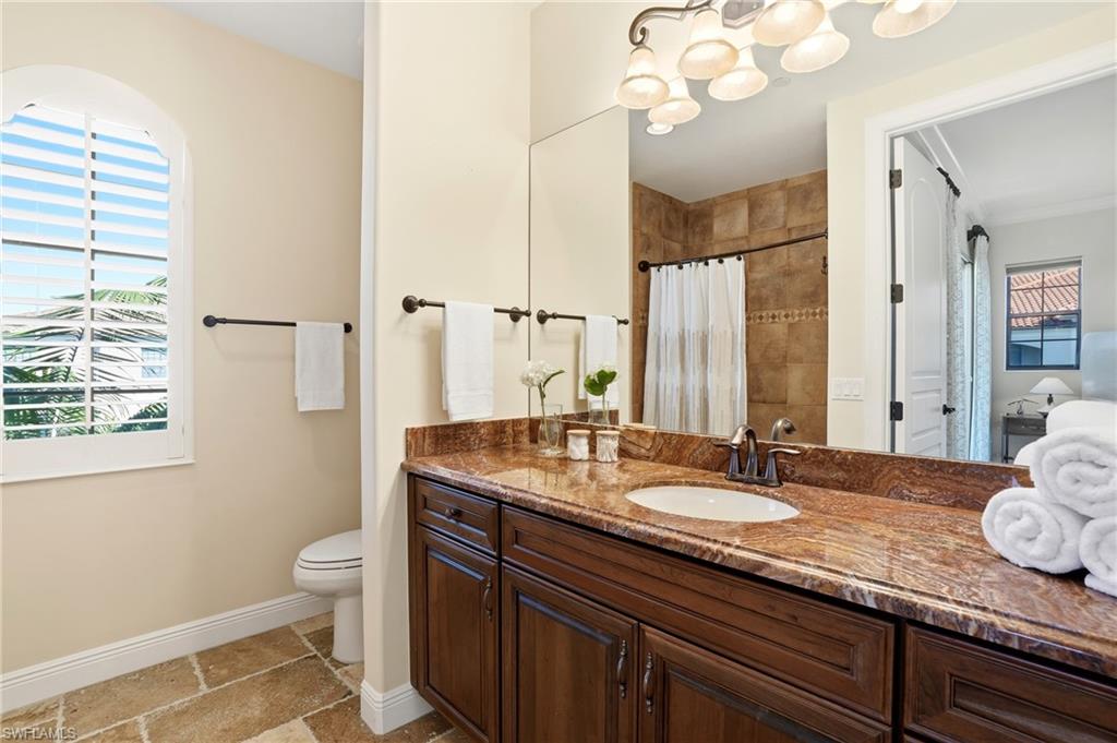 2546 Marquesa Royale Lane, Unit 7302 Naples, FL 34109 - Photo 30 of 46 a bathroom with a granite countertop sink a toilet and a mirror