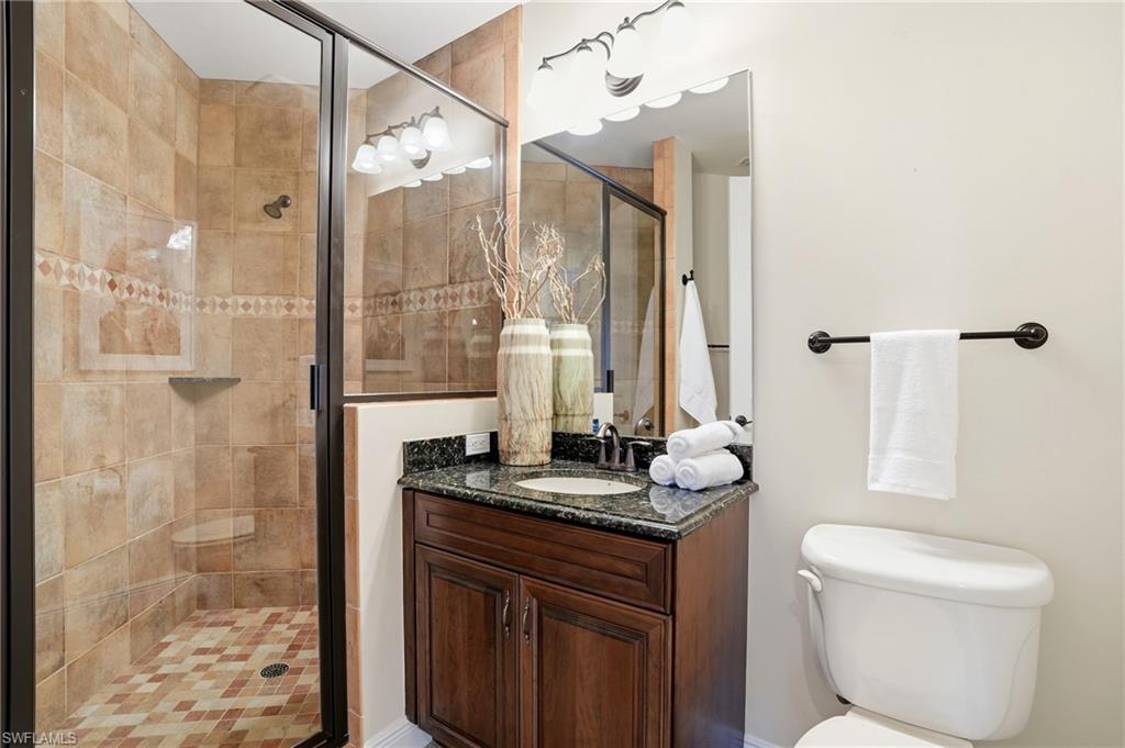 2546 Marquesa Royale Lane, Unit 7302 Naples, FL 34109 - Photo 34 of 46 a bathroom with a granite countertop sink toilet a mirror and shower