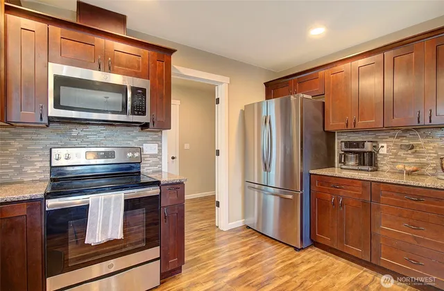 a kitchen with granite countertop wooden cabinets stainless steel appliances and a counter space