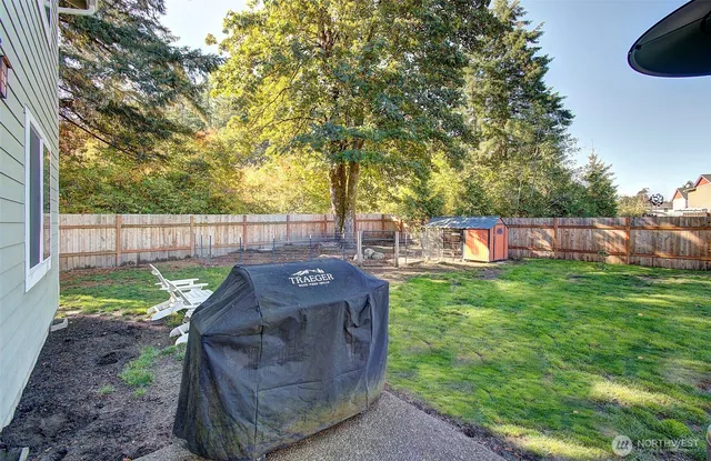 a view of a backyard with large trees and wooden fence
