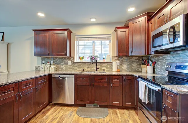 a kitchen with stainless steel appliances granite countertop wooden cabinets a sink and dishwasher
