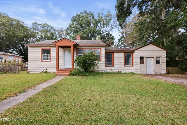 a front view of house with yard and trees in the background