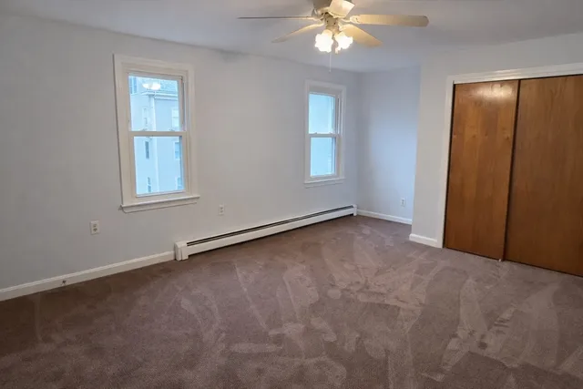 an empty room with windows and chandelier fan