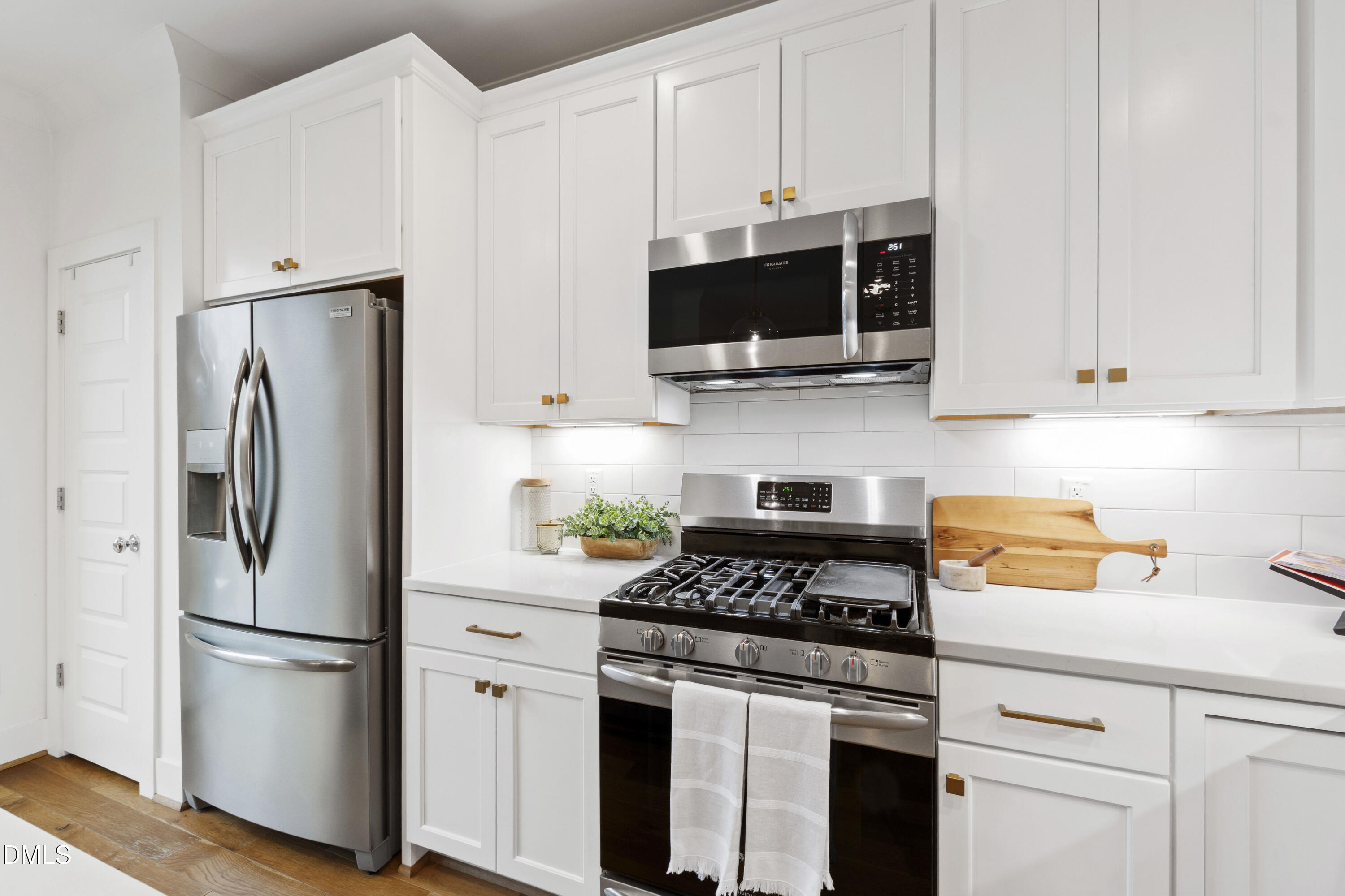 718 Peakland Place Raleigh, NC 27604 - Photo 25 of 48 a kitchen with stainless steel appliances white cabinets and a stove a refrigerator with wooden floors