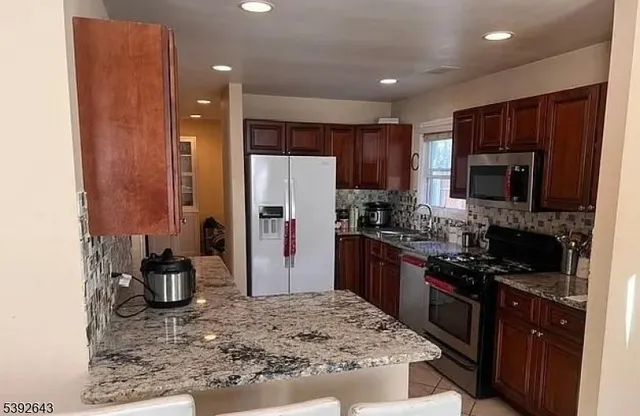 a kitchen with granite countertop a stove top oven microwave and refrigerator