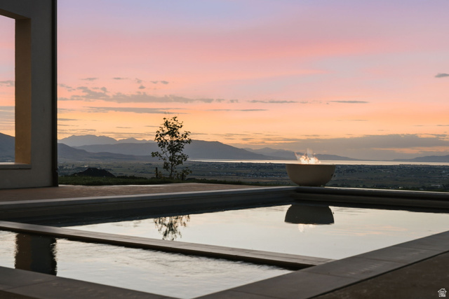 923 North Emery Lane Elk Ridge, UT 84651 - Photo 90 of 101 Outdoor water feature with stone coping, a built-in fire bowl, and a distant mountain and water backdrop