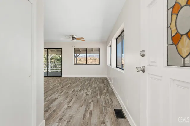 a view of hallway with window and wooden floor