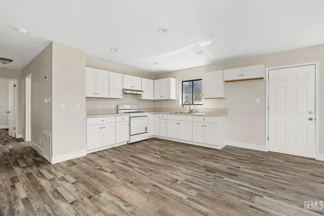 a large kitchen with a stove a sink dishwasher and a refrigerator with wooden floor