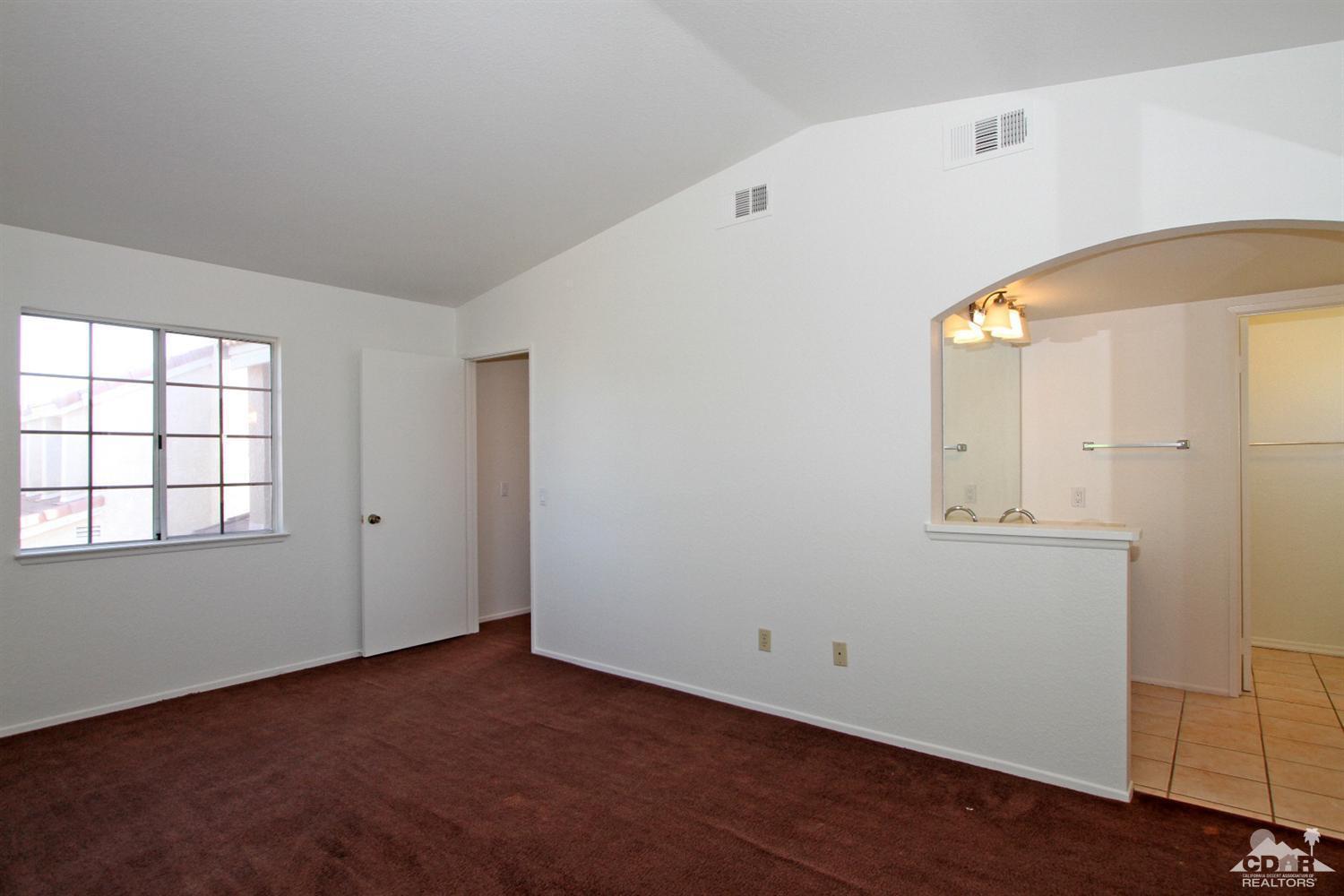 45810 Rogue River Road Indio, CA 92201 - Photo 14 of 25 an empty room with wooden floor and mirror