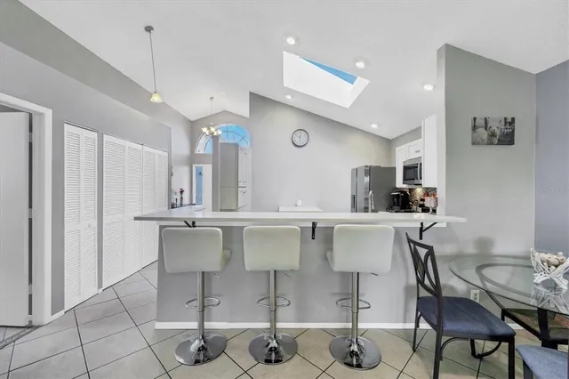 a kitchen with stainless steel appliances kitchen island granite countertop a dining table chairs and a refrigerator