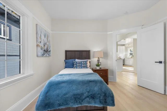 a view of a hallway with wooden floor and a bathroom