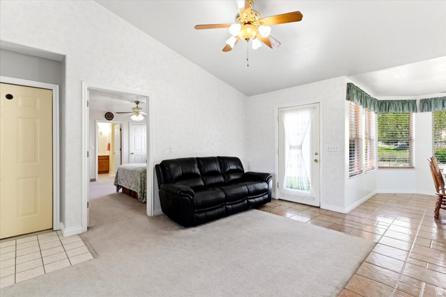 72 Canal Bank Road Garland, UT 84312 - Photo 7 of 40 Living area featuring a textured white wall finish, a ceiling fan with light fixture, a bay window with horizontal blinds, and a combination of light-colored carpet and tiled flooring