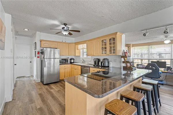 a kitchen with stainless steel appliances granite countertop a stove refrigerator a dining table and chairs with wooden floor