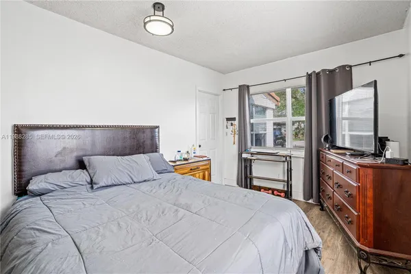 a bedroom with a large bed and a flat tv screen on dresser