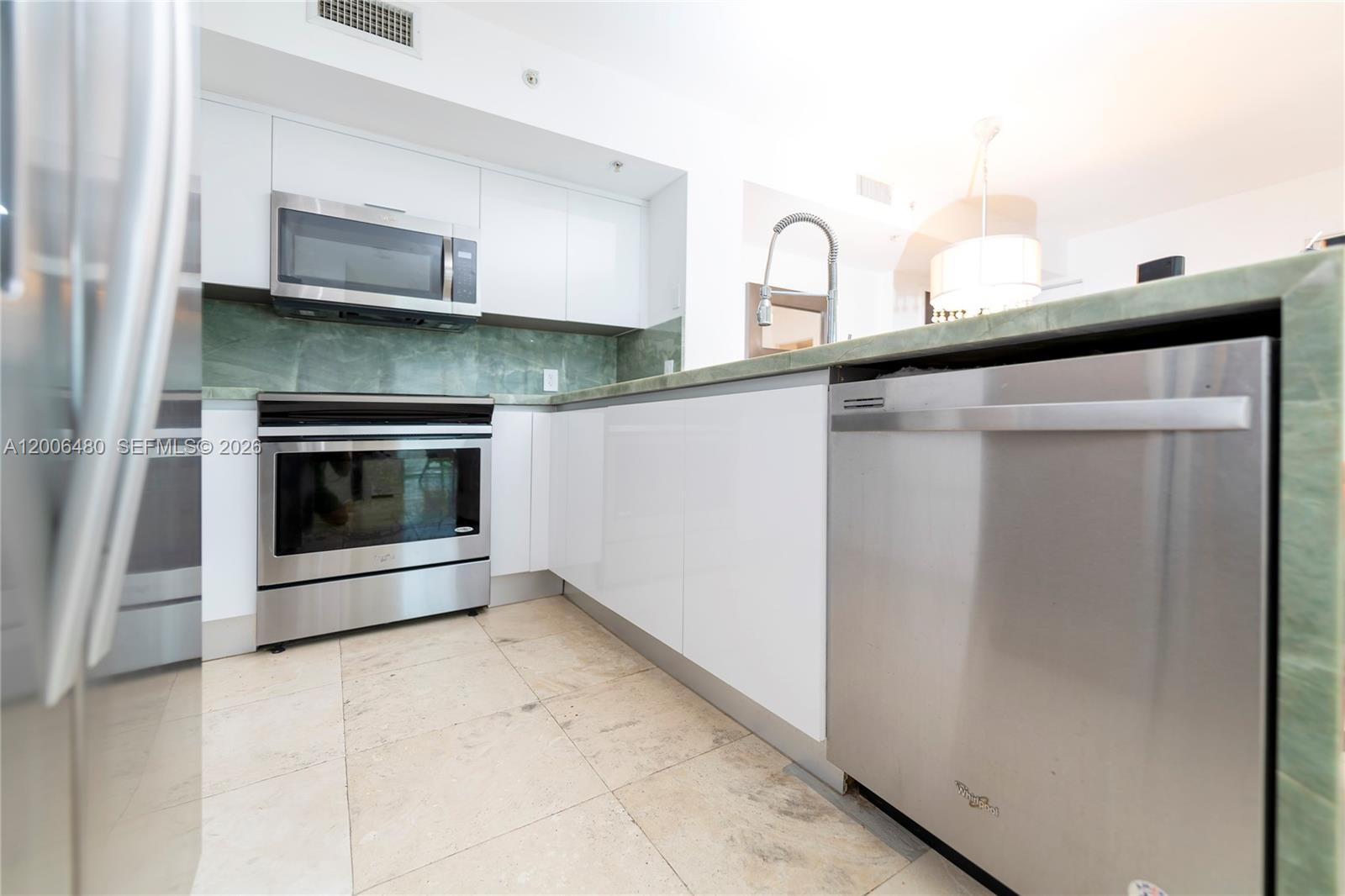 90 Alton Road, Unit 2304 Miami Beach, FL 33139 - Photo 16 of 16 a kitchen with granite countertop a stove and a microwave