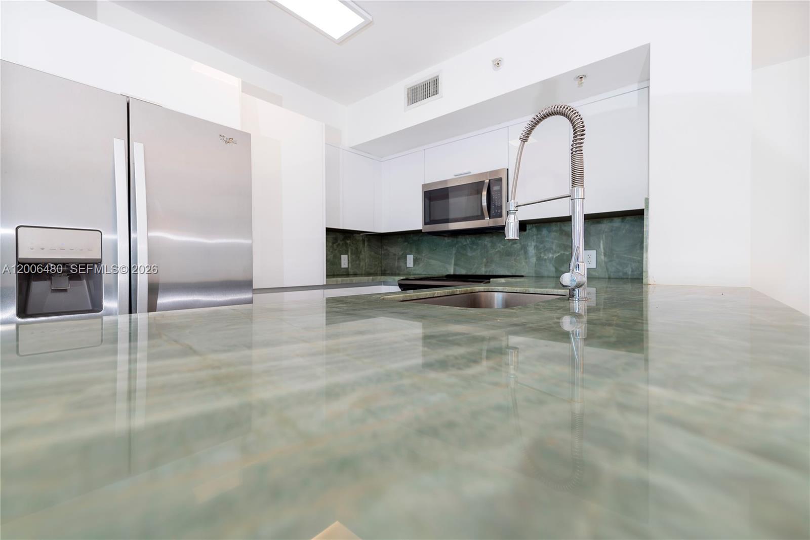 90 Alton Road, Unit 2304 Miami Beach, FL 33139 - Photo 5 of 16 a kitchen with kitchen island granite countertop a sink stainless steel appliances and cabinets