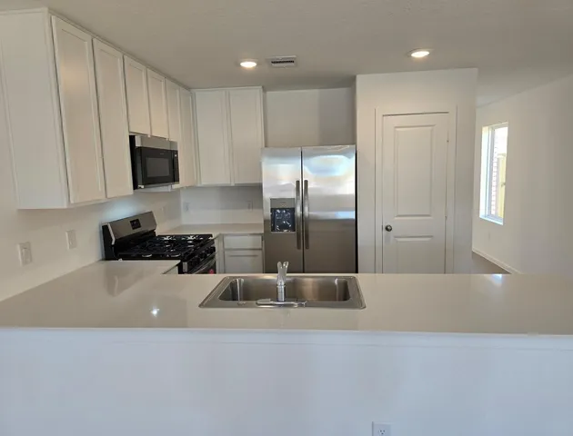 a kitchen with a refrigerator a microwave a sink and cabinets