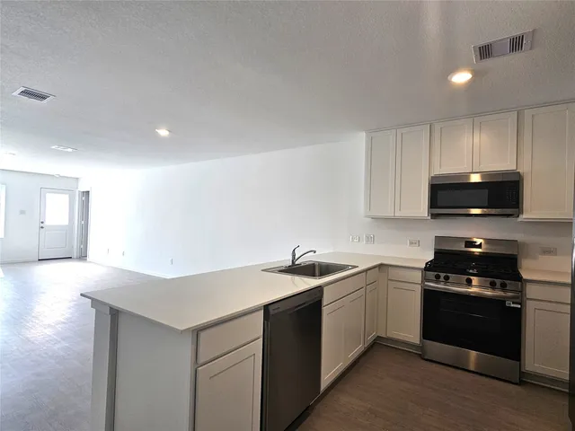 a kitchen with stainless steel appliances a sink a stove a microwave a sink a refrigerator and cabinets