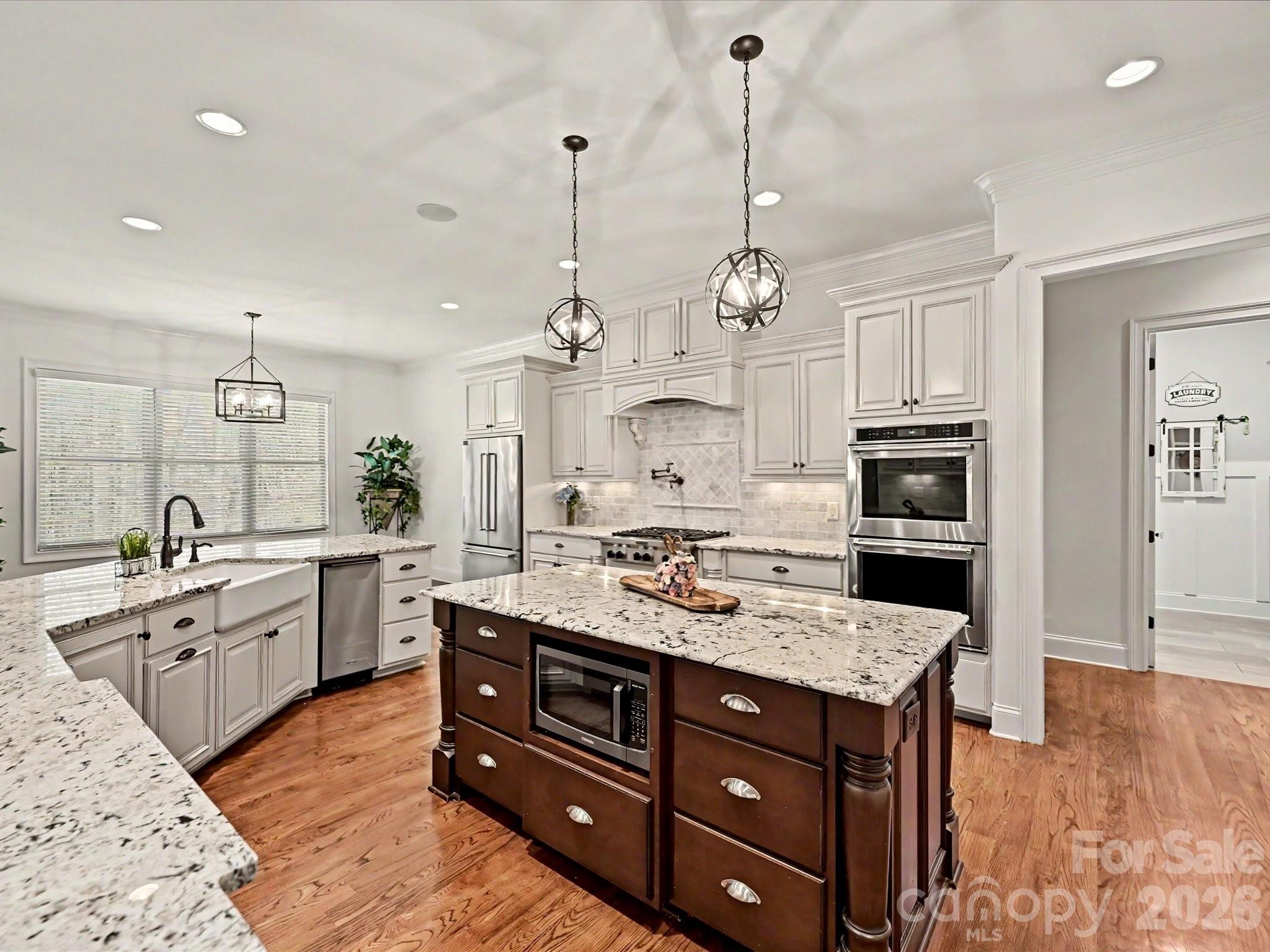 a large kitchen with stainless steel appliances granite countertop a stove oven and a white cabinets