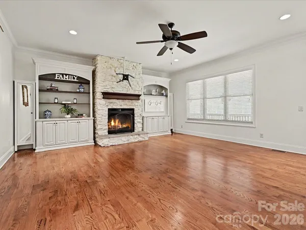 a view of a livingroom with a fireplace a ceiling fan and windows