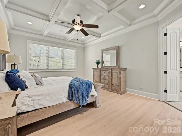 a spacious bedroom with a large bed a chandelier and windows