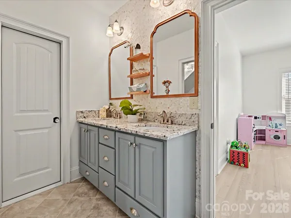 an empty room with chandelier fan and windows