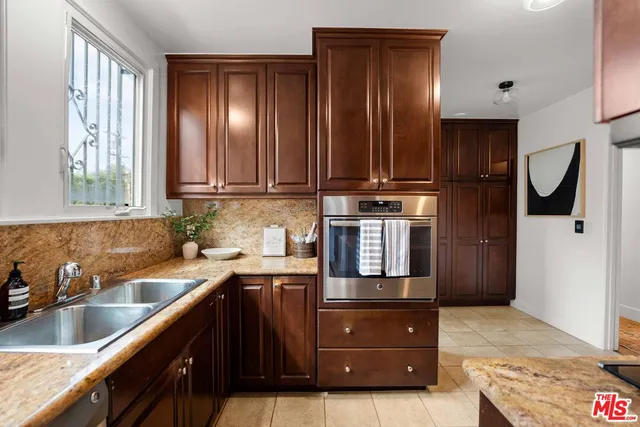 a kitchen with stainless steel appliances granite countertop wooden cabinets a sink and a refrigerator