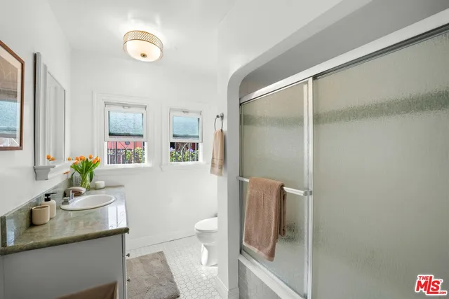 a bathroom with a granite countertop sink mirror vanity and toilet