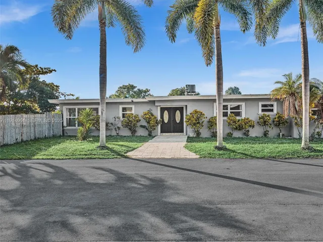 a view of a house with a yard and palm trees