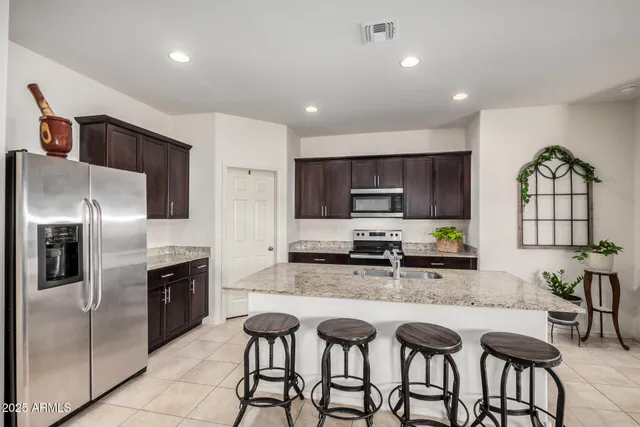 a kitchen with granite countertop a table chairs microwave and refrigerator